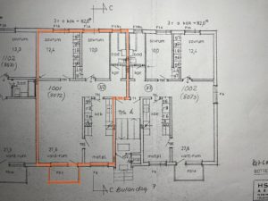 Arkitektonisk planlösning som visar en detaljerad layout av rum inklusive sovrum, vardagsrum och badrum. Olika mått och etiketter anger mått och rumsfunktioner. En orange kontur framhäver vissa delar av planen.