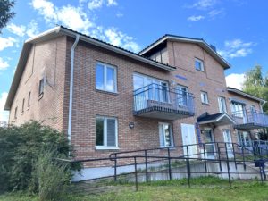 Ett tvåvåningshus i tegel med balkonger. I bakgrunden syns en blå himmel.