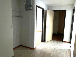 Hall med ljusa väggar och gråfärgat golv. Flera dörröppningar leder till lägenhetens olika rum.