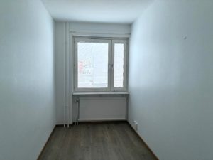 Mindre sovalkov med vita väggar, ett fönster samt träfärgat golv.