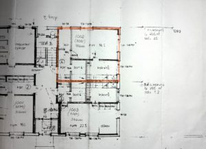 Planlösning för ett flerfamiljshus med flera markerade rum och mått. En lägenhet är markerad med orange markering, vilket markerar dess rum och planlösning.