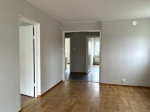 Foto från vardagsrummet som visar hallen längst bort i bild och dörröppningar som leder till lägenhetens andra rum.