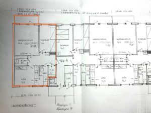 Planlösning för ett flerfamiljshus med flera markerade rum och mått. En lägenhet är markerad med orange markering, vilket markerar dess rum och planlösning.